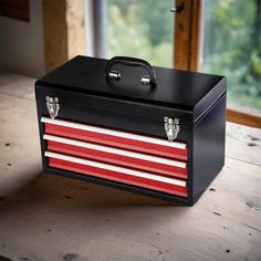 an old toolbox with red, white and blue stripes on the side sitting on a wooden table