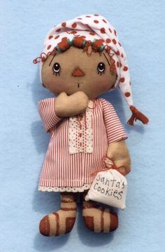 a small doll with a red and white dress holding a cookie in her hand on a blue background