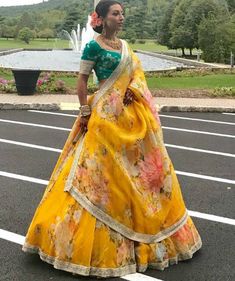 Make a statement in this gorgeous yellow floral lehenga featuring a rich organza fabric with eye-catching floral prints throughout. It comes with a contrasting green art silk blouse decorated with beautiful embroidery work. Complete the look with the yellow organza dupatta. This circular lehenga is perfect for weddings and festivals when you want to look your absolute best. #yellowlehenga #yellowlehengas #yellowlehengacholi #yellowlehengadress #yellowlehengadesigns #yellowlehengadesign #yellowcolorlehenga #designeryellowlehenga Organza Bridal Lehenga, Haldi Outfit For Bride, Dori Work, Haldi Outfits, Haldi Outfit