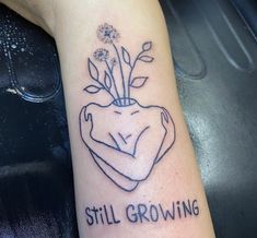 a tattoo on the arm that says still growing with a flower in its center and an arrow above it