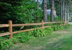 a wooden fence in front of some trees