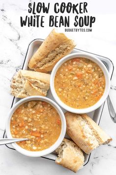 three bowls of slow cooker white bean soup on a tray with two pieces of bread