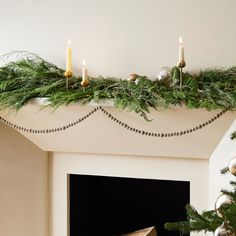 a mantel decorated with greenery and candles