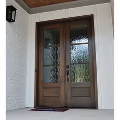 the front door to a house with two glass doors and a rug on the floor