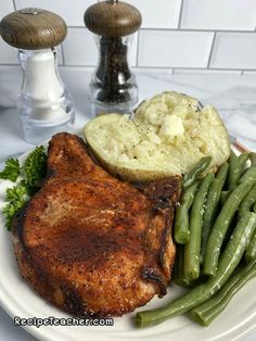 a white plate topped with meat, potatoes and green beans