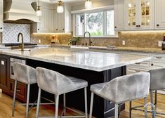 a large kitchen island with three stools in front of it and an oven on the other side