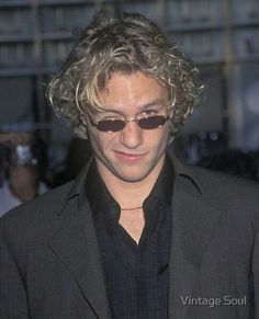 a man with curly hair and sunglasses looking at his cell phone