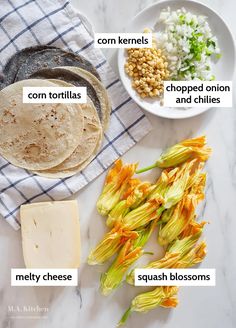 the ingredients to make mexican food laid out on a white marble counter top, including tortillas, corn kernels, chopped onion and cheese