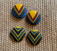 three buttons with different designs on them sitting on a cloth covered tablecloth or carpet