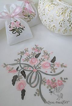 two white vases sitting next to each other on top of a table with embroidered designs