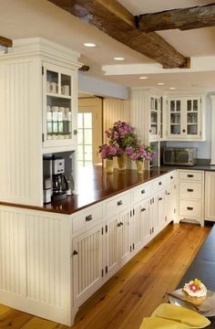 a large kitchen with white cabinets and wood flooring on the counter top, along with an island in the middle