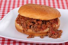 a sloppy joe sandwich on a plate with a red and white checkered tablecloth