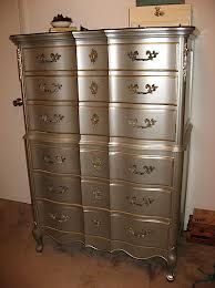 an antique chest of drawers is painted silver