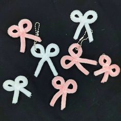 six pink and white bows are hanging from the side of a black background, with two key chains attached to them