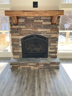 a living room with a fire place in the center and wood flooring on the other side