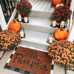 pumpkins and flowers are on the front steps of a house with a welcome mat that says hey there pumpkin