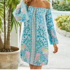 Stand Out In This Stunning Lilly Pulitzer Nevie Off Shoulder Dress In The Vibrant Caribbean Citrus Engineered Pattern. The 3/4 Ruffle Sleeves And Off-The-Shoulder Neckline Add A Touch Of Femininity, While The Tasseled Accents Give It A Playful Vibe. This Dress Is Perfect For Any Occasion - Whether It's A Party Or A Casual Day Out. Made Of 100% Rayon, This Dress Is Machine Washable For Easy Care. The Pullover Closure And Above-The-Knee Length Make It A Comfortable And Practical Choice. The Dress Long Sleeve Summer Dress In Blue, Blue Long Sleeve Summer Dress, Light Blue Long Sleeve Summer Dress, Light Blue Long Sleeve Mini Dress For The Beach, Blue Long Sleeve Mini Dress For Garden Party, Light Blue Long Sleeve Mini Dress For Beach, Light Blue Off-shoulder Beach Dress, Light Blue Off-shoulder Summer Dress, Blue Vibrant Print Dress For Beach Cover-up