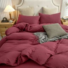 a bed with red sheets and pillows on it