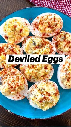 a blue plate topped with deviled eggs on top of a wooden table