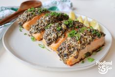 two pieces of salmon on a plate with lemon wedges and parsley garnish