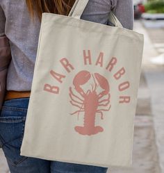 a woman carrying a tote bag that says bar harbor with a lobster on it