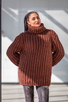 a woman standing in front of a building wearing a brown sweater