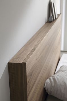 a bed with a wooden headboard next to a white wall in a small room