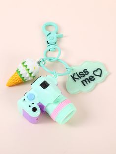 a key chain with a camera, ice cream cone and kiss me tag on it