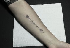 an arrow tattoo on the arm with arrows and stars above it, in black ink