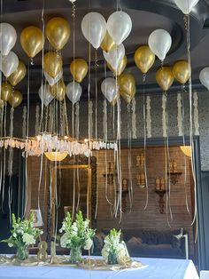 balloons and streamers are hanging from the ceiling in front of a table at a party