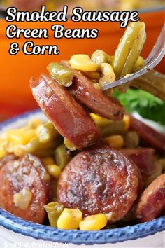 smoked sausage, green beans and corn in a blue bowl with a spoon on top