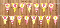 a happy birthday banner is hanging on a fence with flowers and polka dot pennants