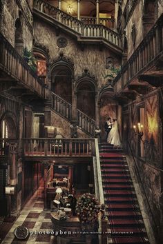 a bride and groom standing at the top of stairs in an old castle like building