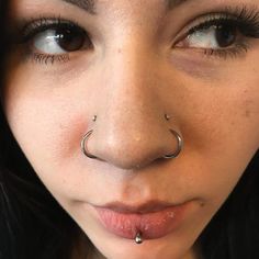 a close up of a woman with a nose ring and piercing on it's nose