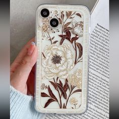 a hand holding an iphone case that has flowers on it and is next to a book