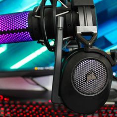 a close up of a microphone and headphones on a computer desk with colorful lights in the background