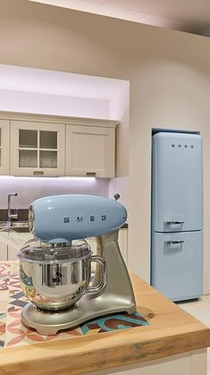 a kitchen with an old fashioned mixer on the counter and a refrigerator in the background