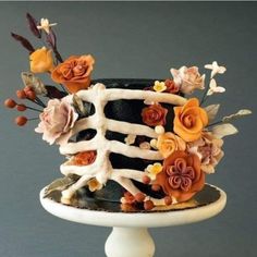 a black and white cake with orange flowers on it's tiered stand, against a gray background