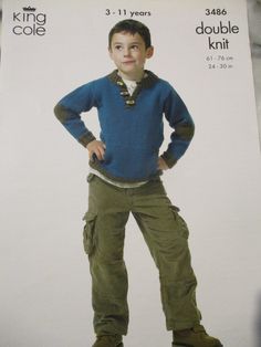 a young boy in a blue sweater and khaki pants standing with his hands on his hips