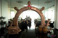 there is a large wooden arch in the middle of a room with people standing around it