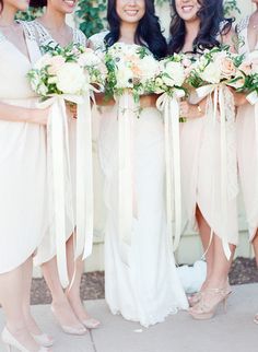 the bridesmaids are all dressed in white dresses and holding their bouquets together