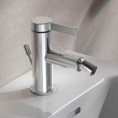 a chrome faucet sitting on top of a white sink next to a wall