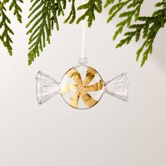 a glass ornament hanging from a christmas tree with gold and white candy canes