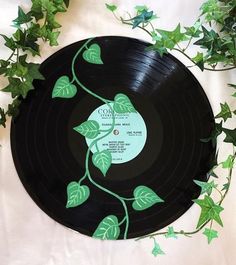 a vinyl record with green leaves on it sitting next to some ivy growing on the wall