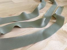 a pair of gray satin ribbon laying on top of a wooden floor