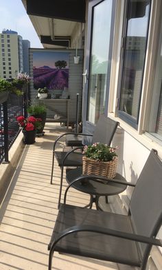 two chairs and a table on a balcony with flowers in the potted planter