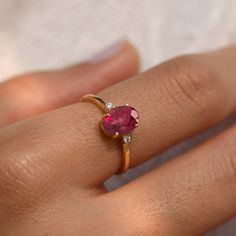 a woman's hand with a pink stone ring on her left hand and diamond band