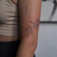 a woman's arm with a tattoo on it that has leaves growing out of it