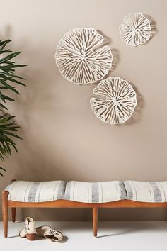 three circular wall hangings above a bench with shoes on the floor next to it