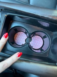 a woman's hand pointing at the center console of a car with two speakers in it